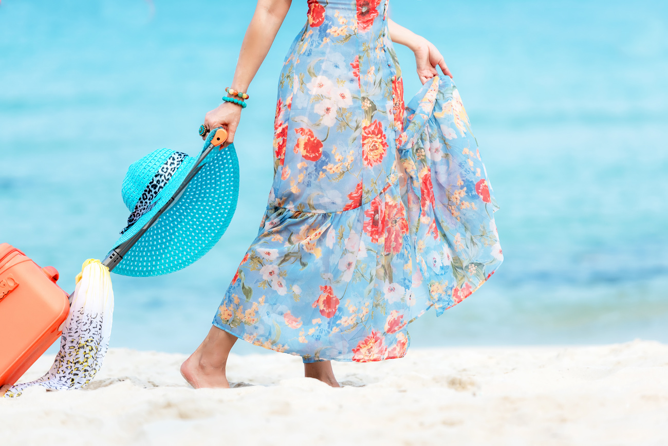 Travel Plan. Hand women traveler holding orange luggage walking on the beach. Traveler and Tourism planning trips summer vacations with Traveler's accessories summertime. Summer Concept